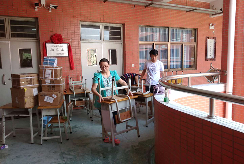 银河集团(galaxy)志愿者及家长用消毒液擦拭桌椅